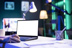 Closeup of person using a laptop showing isolated copyspace mockup template. An individual utilizing an electronic device on the table that is displaying a blank white screen. photo
