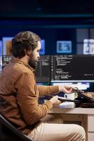 Man packing laptop after finishing doing software quality assurance and reading source code. Developer placing notebook in backpack after inspecting coding on desktop PC and finding all issues photo