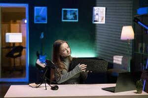 Entertainer presenting keyboard from brand sponsoring , urging viewers to buy it. Girl does influencer marketing by advertising computer peripherals to audience in studio photo