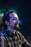 Side view profile of bearded man sitting on a chair. The image is showing a closeup shot of a positive male individual in a thoughtful gaze. photo