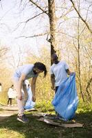 Activists team collecting garbage to fix pollution problems within the natural forest, protecting the environment. Volunteers doing community service to clean the woods from trash and plastic. photo