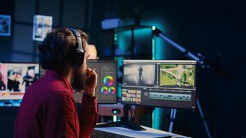 editor polishing raw footage, applying modern editing techniques in order to enhance sound and visual quality. Videographer adjusting clips while listening music in headphones photo