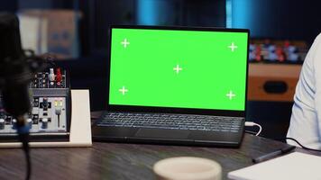 Close up of green screen laptop next to podcast microphone used to record discussions for online livestreaming channel. Mockup notebook in studio with streaming sound capturing and recording equipment photo