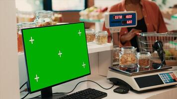 Merchant selling goods next to pc with greenscreen at checkout, locally grown fruits and veggies for sustainable lifestyle. Computer monitor running isolated chromakey display and mockup. photo