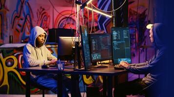 Evil hackers doing data breaches and financial theft in graffiti painted hideout. Rogue programmers stealing users bank account credentials, targeting low security passwords photo