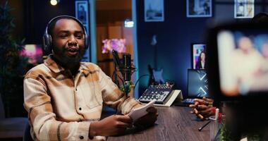 BIPOC man on podcast conversating with guest during marathon stream for charitable cause. Host in apartment studio chatting with celebrity, gathering donations from fans during online show photo