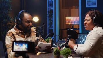 Internet show host making woman laugh, cracking jokes during comedy focused podcast filmed with professional gear. Talking show interviewer broadcasting live from studio with recording camera photo