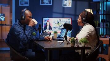 Show host recording podcast, enjoying cup of coffee and nice conversation with guest. African american man using professional audio devices for flawless sound quality while live chatting with woman photo