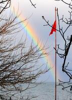 Red flag on the background of a multi-colored rainbow over the sea, the Black Sea photo