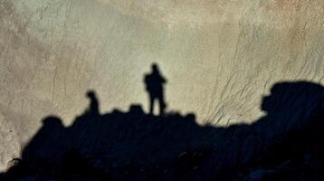 Shadow of a man against a background of dry cracked clay, cracks on the ground. photo
