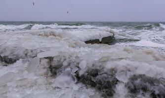 Frozen Black Sea, ice-covered and frozen coastal rocks in the piers, harsh winter photo