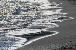 Bright reflections on the water on a sunny day on the sandy shore of the Black Sea photo