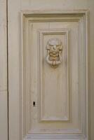 Traditional copper handle and door knocker on wooden doors of old houses in Malta photo