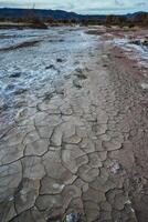 Cracked red clay and white salt on the surface in a dried riverbed in the desert of New Mexico, USA photo