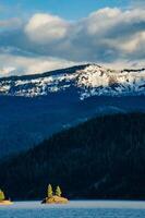 Mountains in the snow, overgrown with wood. Thick clouds over the mountains. photo
