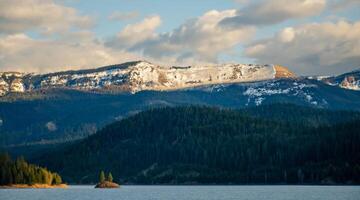 Mountains in the snow, overgrown with wood. Thick clouds over the mountains. photo