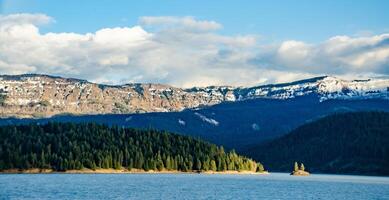 Mountains in the snow, overgrown with wood. Thick clouds over the mountains. photo