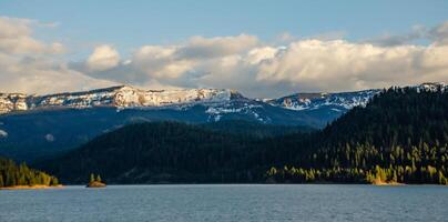 Mountains in the snow, overgrown with wood. Thick clouds over the mountains. photo