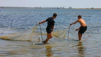 ODESSA, UKRAINE - JUNE 30, 2007 Fishermen catch fish with a net in a shallow pond, Tiligulsky Estuary Ukraine photo