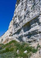 Vertical high rock made of white shell rock near the Black Sea coast near Sozopol, Bulgaria photo