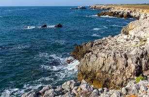 Seascape on the Black Sea, high steep stone coast with inaccessible rocks photo