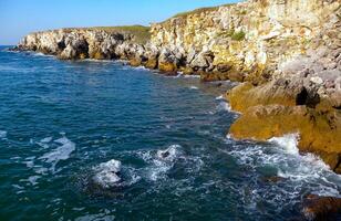 Seascape on the Black Sea, high steep stone coast with inaccessible rocks photo