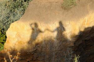 Shadow on yellow clay of two people holding hands photo