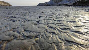 Waves on a muddy bottom in a sea channel at low tide photo