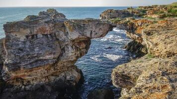 Large arch in coastal rocks made of shell rock near the village of Tyulenovo photo