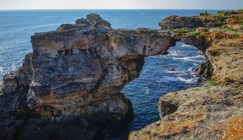 Large arch in coastal rocks made of shell rock near the village of Tyulenovo photo