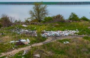 Heaps of plastic trash on the shore of the reservoir. Ecology of nature photo