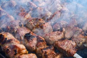 Pork meat is fried on smoking coals in the grill photo