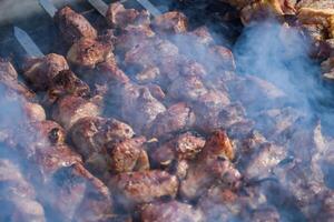 Pork meat is fried on smoking coals in the grill photo