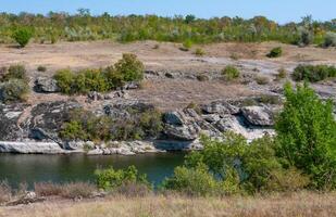 The bed of a slowly flowing river among granite banks overgrown with picturesque vegetation, Ukraine photo