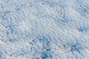 Weathered ice and frozen snow in the form of needle crystals on the bank of the Tiligul Estuary on a sunny day photo