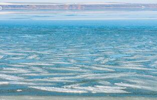 Ice floating near the shore in the form of oblong ice floes, rolled around by waves and a storm in the Tiligul estuary photo