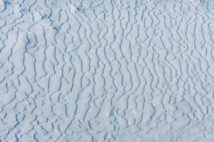Weathered ice and frozen snow in the form of needle crystals on the bank of the Tiligul Estuary on a sunny day photo
