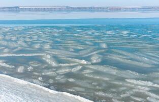 Ice floating near the shore in the form of oblong ice floes, rolled around by waves and a storm in the Tiligul estuary photo