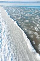 Ice floating near the shore in the form of oblong ice floes, rolled around by waves and a storm in the Tiligul estuary photo
