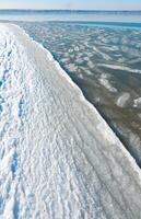 Ice floating near the shore in the form of oblong ice floes, rolled around by waves and a storm in the Tiligul estuary photo