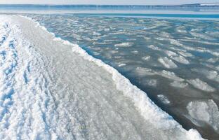 Ice floating near the shore in the form of oblong ice floes, rolled around by waves and a storm in the Tiligul estuary photo