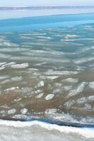 Ice floating near the shore in the form of oblong ice floes, rolled around by waves and a storm in the Tiligul estuary photo