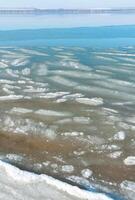 Ice floating near the shore in the form of oblong ice floes, rolled around by waves and a storm in the Tiligul estuary photo