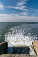 Waste water is poured into the estuary, dirty foam. Ecological problems of the reservoir. Hadzhibey estuary, Ukraine photo