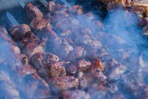 Pork meat is fried on smoking coals in the grill photo