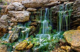 Small waterfall on stones covered with freshwater green algae Enteromorpha sp. photo