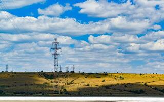Iron structures of a high-voltage power line against a blue sky with clouds photo