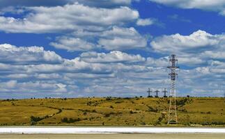 Iron structures of a high-voltage power line against a blue sky with clouds photo
