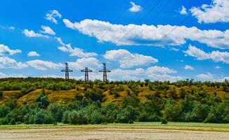 Iron structures of a high-voltage power line against a blue sky with clouds photo