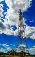 Iron structures of a high-voltage power line against a blue sky with clouds photo